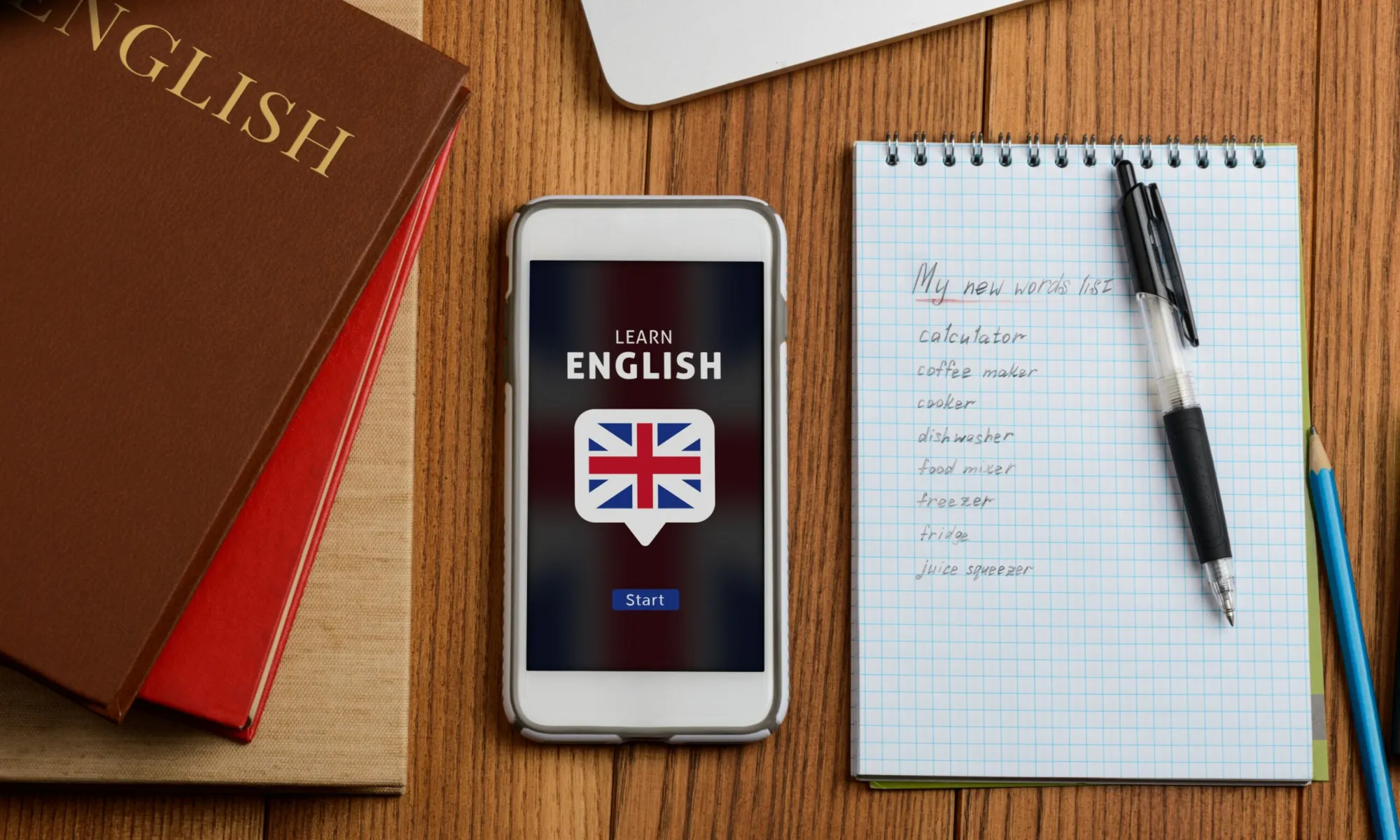 Il telefono mostra la bandiera inglese e accanto c'è un quaderno con un elenco scritto di parole inglesi.