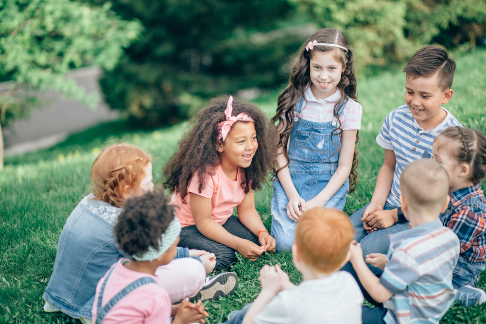 gruppo di bambini seduti sull'erba in cerchio