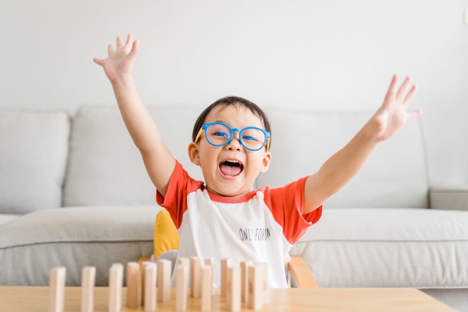 Un bambino felice, intelligente e sicuro di sé ha alzato la mano quando ha vinto il blocco giocattolo di legno a casa.
