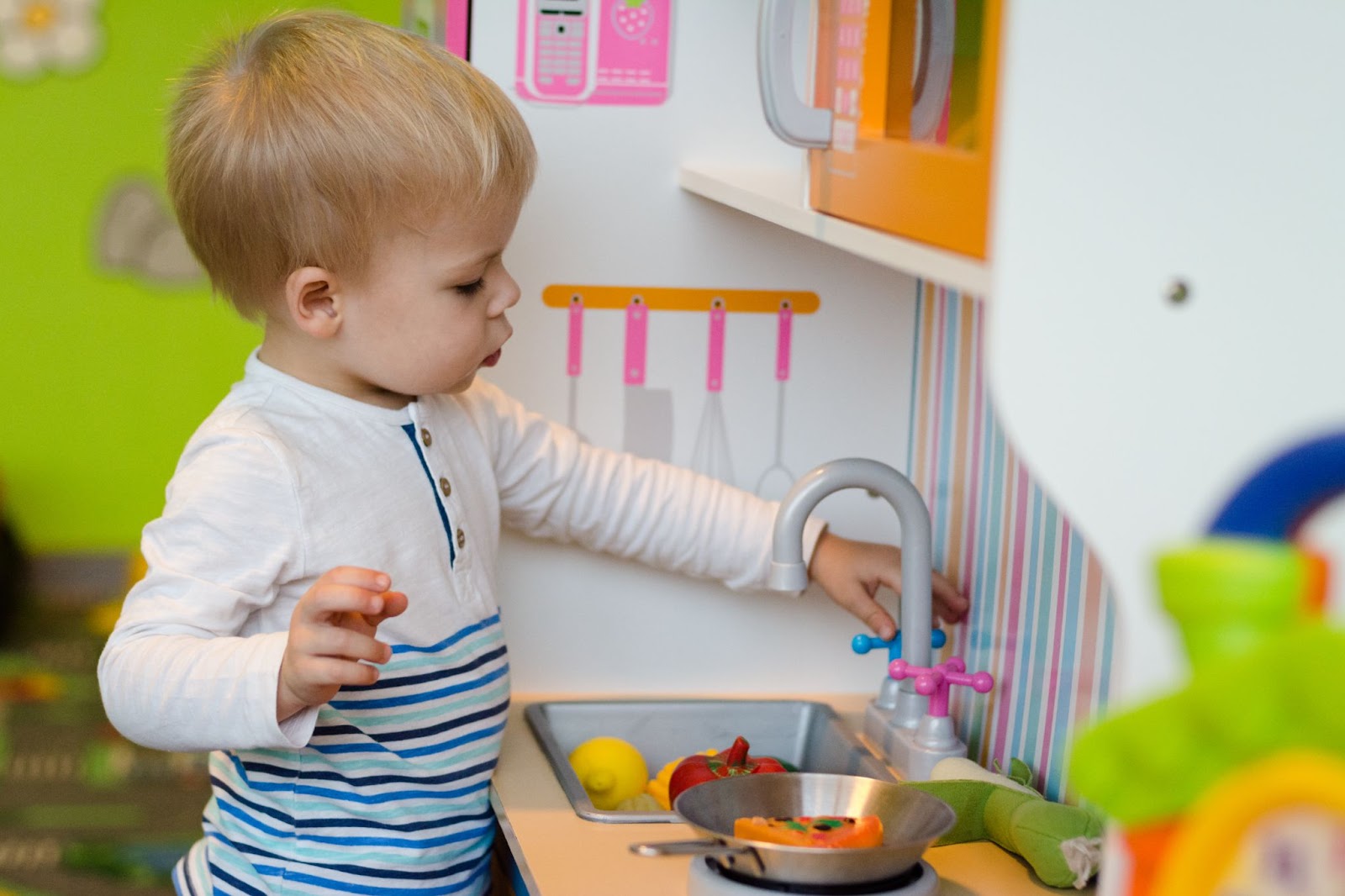 Bambino sta giocando alla preparazione di un pasto su una cucina giocattolo di plastica